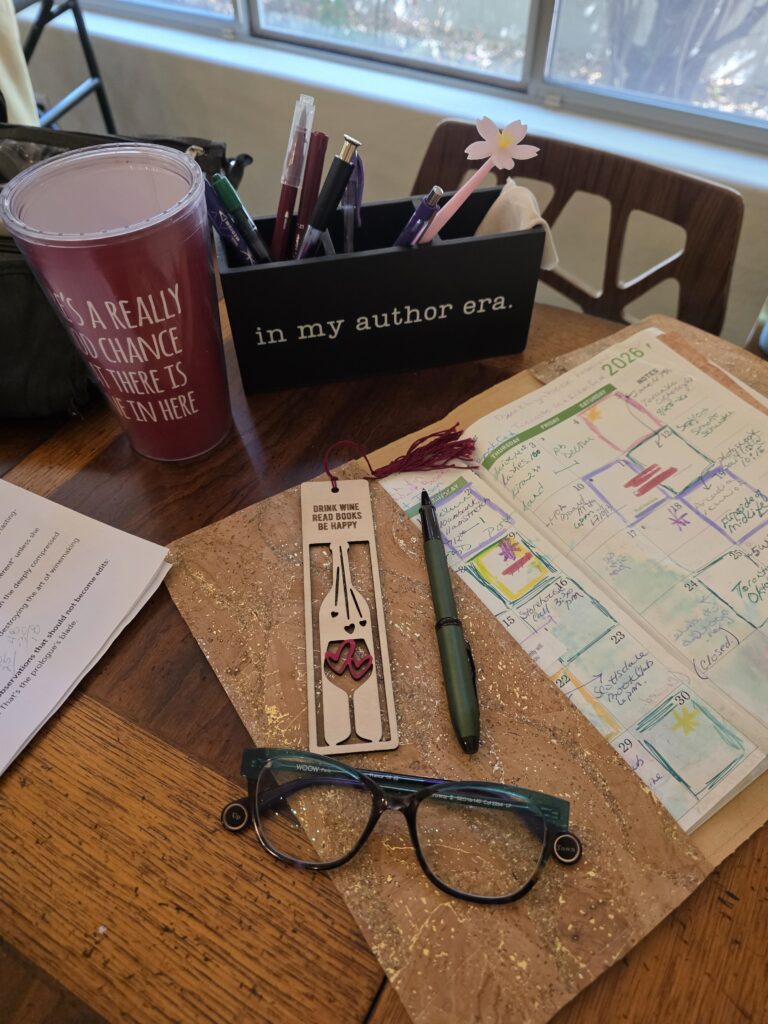 Lea’s writing desk with notebook, pens, and coffee mug.
